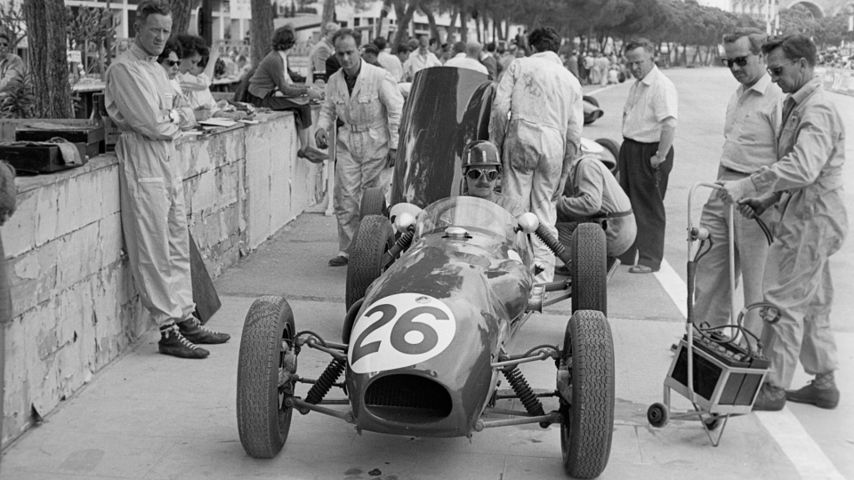 vintage racecar on a track with people standing around it