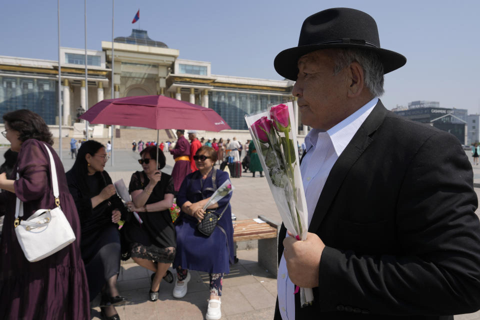 A man holds flowers as he joins an alumni anniversary gathering on Sukhbaatar Square in Ulaanbaatar, Mongolia, Monday, July 1, 2024. (AP Photo/Ng Han Guan)