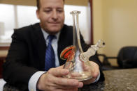 In this Wednesday, Jan. 4, 2017 photo, attorney Jamie Sasson holds a counterfeit Roor bong at his office in Deerfield Beach, Fla. High-end German glass water pipe maker Roor and its American licensee are filing lawsuits against smoke shops and mom-and-pop convenience stores in Florida, California and New York alleging that they are selling Roor counterfeits, violating its trademark. (AP Photo/Lynne Sladky)