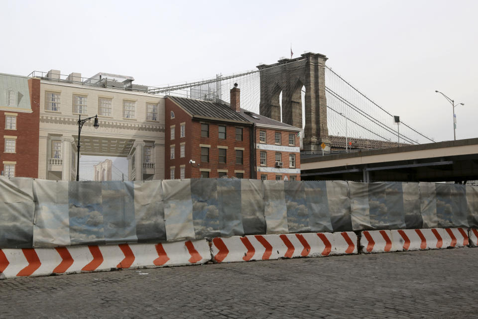 In this Thursday, Feb. 7, 2013 photo, construction materials are stored behind a cloud painted fence on Peck Slip in New York. Nearly four months after Superstorm Sandy hit, the historic cobblestone streets near the water's edge in lower Manhattan are eerily deserted, and among local business owners, there is a pervasive sense that their plight has been ignored by the rest of Manhattan. (AP Photo/Mary Altaffer)