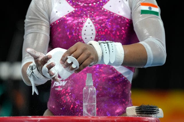 An athlete from India prepares her hands before using the uneven bars in a gymnastics training session ahead of the Birmingham 2022 Commonwealth Games in Birmingham, England