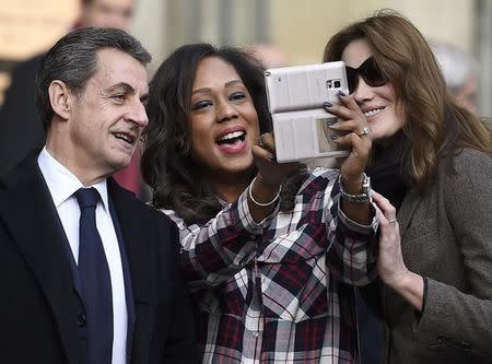 Nicolas Sarkozy, former French president and current head of the Les Republicains political party, and his wife Carla Bruni-Sarkozy pose for a selfie picture as they leave a polling station during the first round of regional elections in Paris, France, December 6, 2015. REUTERS/Eric Feferberg/Pool