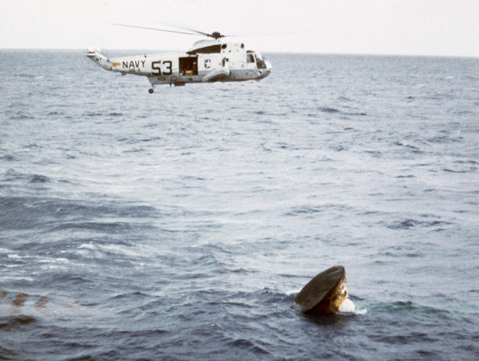 FILE - In this July 24, 1969, file photo, after an eight-day mission on the moon, the Apollo 11 command module lands in the Pacific Ocean and is about to be safely recovered by a U.S. Navy helicopter. The Honolulu Star-Advertiser reported Wednesday, July 24, 2019, the 50th anniversary of the astronaut's return to Earth, that the crew hit the atmosphere at 25,000 mph, creating a fireball that was visible to the crew of the waiting recovery aircraft carrier USS Hornet stationed about 900 miles (1,448 kilometers) southwest of Hawaii. (AP Photo, File)