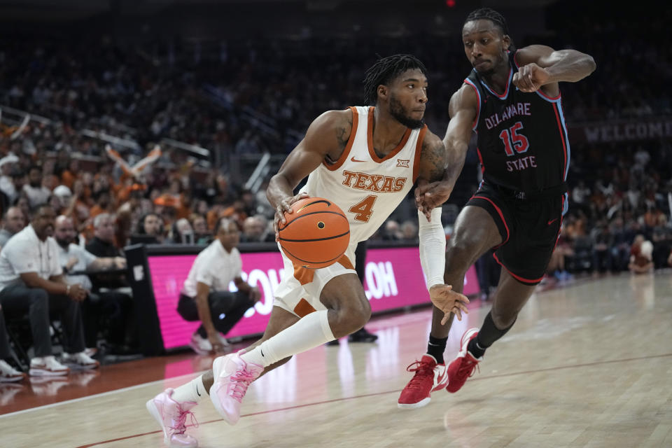 Texas guard Tyrese Hunter (4) drives around Delaware State forward Wesley Oba (15) during the second half of an NCAA college basketball game, Friday, Nov. 10, 2023, in Austin, Texas. (AP Photo/Eric Gay)