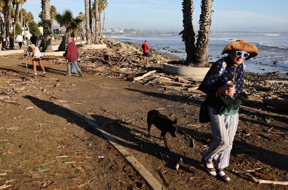 PHOTO: A person attempts to clean up debris washed up by large waves which impacted the beach on Dec. 28, 2023, in Ventura, California (Mario Tama/Getty Images)