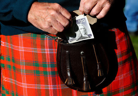 FILE PHOTO: A man puts money in his sporran at the Birnam Highland Games in Scotland, Britain August 30, 2014. Scotland will hold a referendum on independence on September 18. REUTERS/Russell Cheyne/File Photo