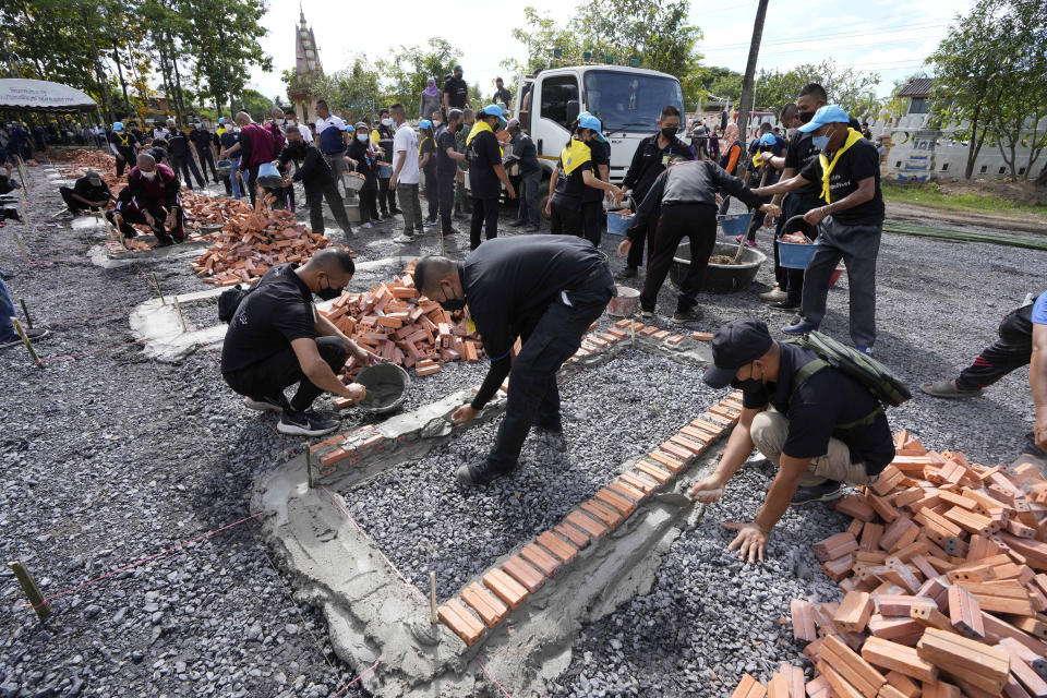 Police officers help lay bricks for cremation furnaces on the grounds of Wat Rat Samakee temple in Uthai Sawan, northeastern Thailand, Monday, Oct. 10, 2022. Thailand to cremate the bodies of the mostly young victims of last week's massacre at a day care center by a former policeman. (AP Photo/Sakchai Lalit)