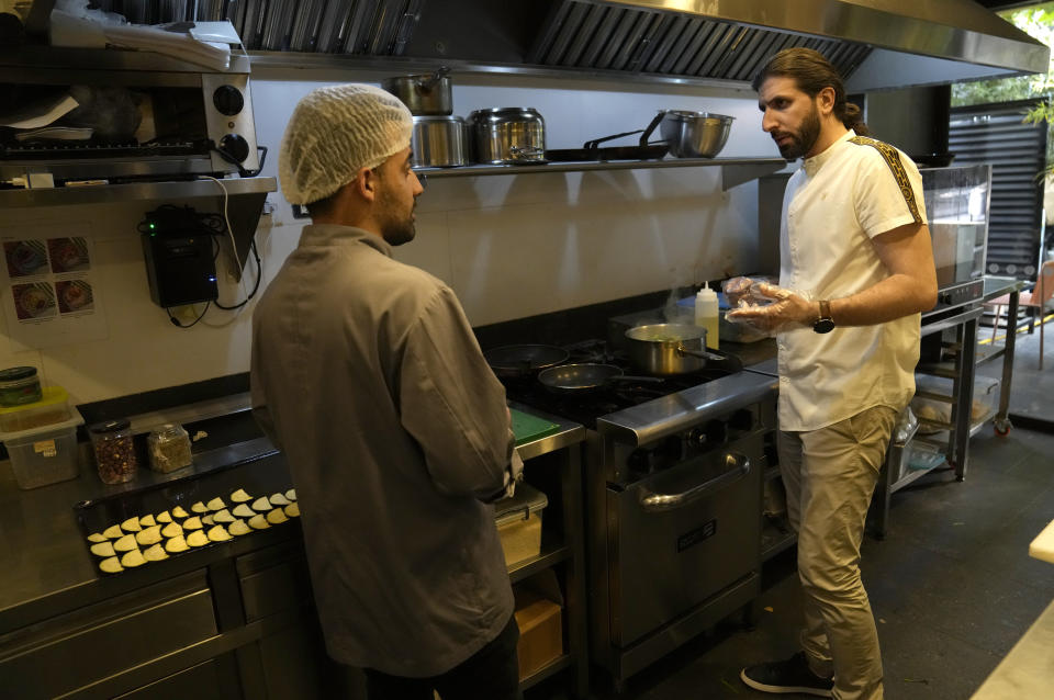 Abbas Bazzi gives directions to a chef at Le Marché Bio, the organic cafe and grocery store he co-owns, in Beirut, Lebanon, on May 30, 2023. Bazzi, who grew up in a secular family but was interested in Islam from an early age, hopes to travel to the Muslim holy city of Mecca, Saudi Arabia, for his fourth Hajj pilgrimage this month. (AP Photo/Hussein Malla)