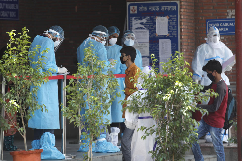 Doctores en equipos de protección revisan la documentación de personas con familiares ingresados en un hospital para enfermos de COVID-19, en Nueva Delhi, India, el 23 de junio de 2020. (AP Foto/Manish Swarup)