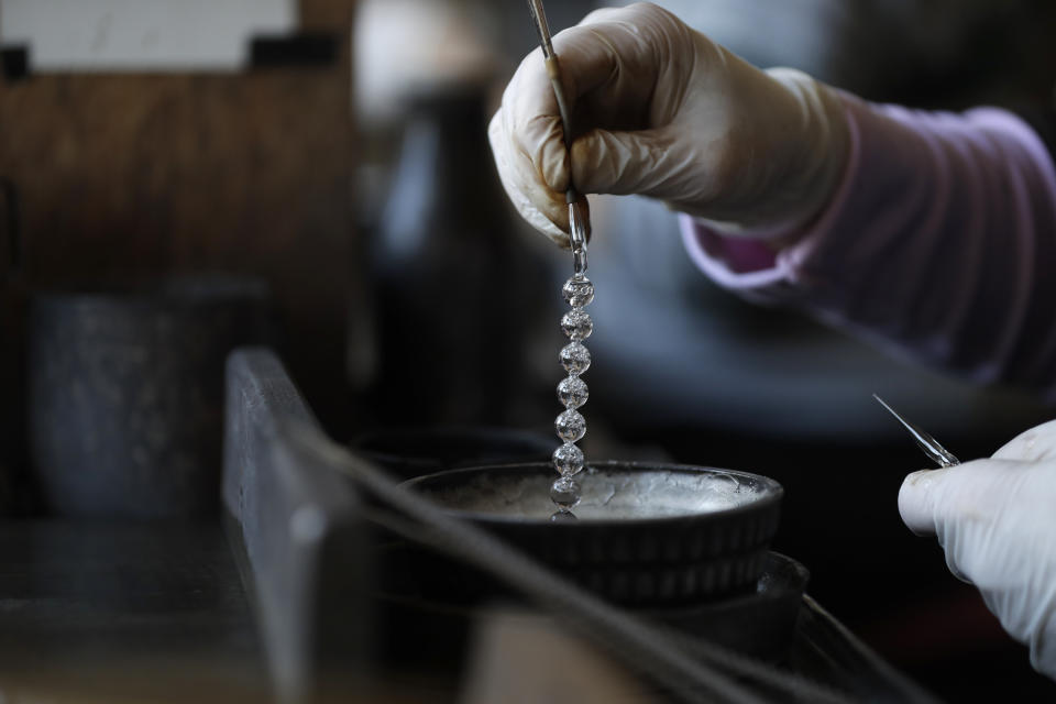 In this picture taken on Wednesday, Nov. 28, 2018, a worker makes small glass blown beads for Christmas decorations in the village of Ponikla, Czech Republic. The small family business in a mountainous village in northern Czech Republic is the last place in the world where traditional Christmas decorations are made from glass beads blown and painted by hand. (AP Photo/Petr David Josek)