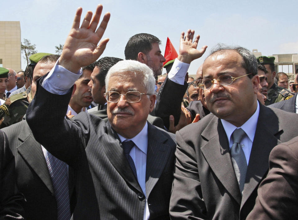 FILE - In this Wednesday, Aug. 13, 2008, file photo, Palestinian President Mahmoud Abbas, left, waves goodbye to the coffin of Palestinian poet Mahmoud Darwish, as Israeli Arab lawmaker Ahmed Tibi, right, watches after his funeral at Abbas' headquarters in the West Bank city of Ramallah. A new proposal by Israel's powerful and outspoken foreign minister has sparked outrage among the country's Arab minority and added new complications to U.S. Secretary of State John Kerry's long shot Mideast peace mission. (AP Photo/Nasser Shiyoukhi, File)