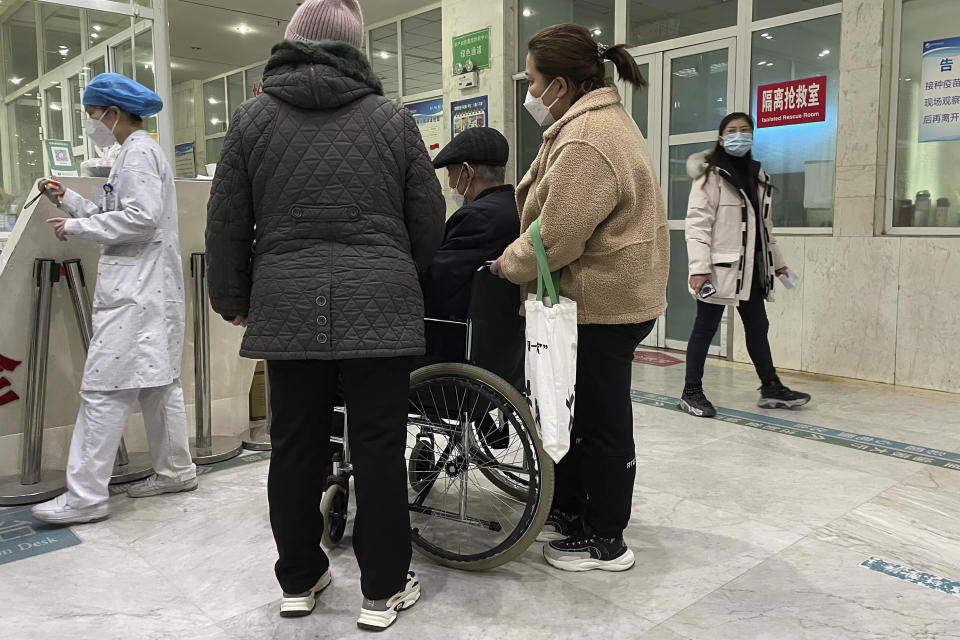 A man in a wheelchair is helped at the Zhuozhou Hospital in Zhuozhou city in northern China's Hebei province on Wednesday, Dec. 21, 2022. China only counts deaths from pneumonia or respiratory failure in its official COVID-19 death toll, a Chinese health official said, in a narrow definition that limits the number of deaths reported, as an outbreak of the virus surges following the easing of pandemic-related restrictions. (AP Photo)