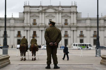 A police officer stands guard in front of the La Moneda presidential palace in Santiago, September 9, 2014. REUTERS/Ivan Alvarado