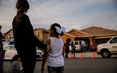 Neighbours stand outside the house where the children were found - Credit: Los Angeles Times