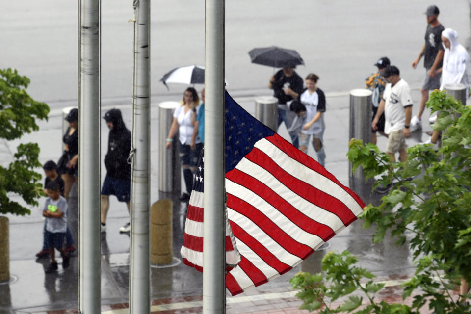 A United States flag flies at half-staff after a Fourth of July parade shooting in nearby Highland Park, Ill., while lines of fans wait to go through added security at Guaranteed Rate Field, Monday, July 4, 2022, in Chicago before a baseball game between the Chicago White Sox and the Minnesota Twins. (AP Photo/Paul Beaty)