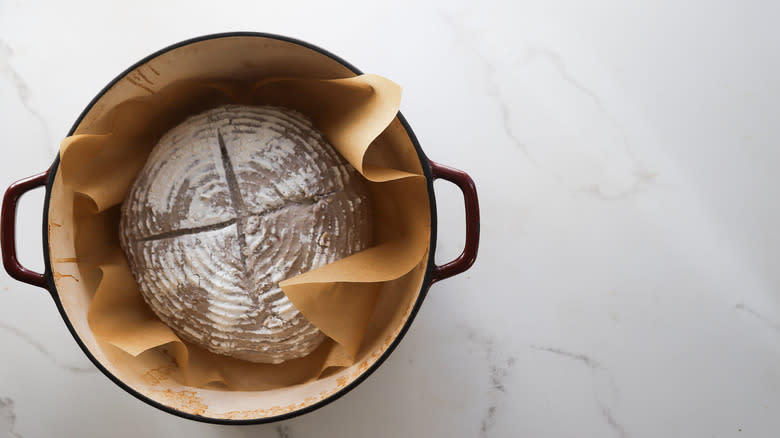 Raw dough in parchment-lined Dutch oven