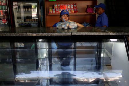 A saleswoman holds bags of bread as she waits for customers at a bakery in Caracas, Venezuela March 17, 2017. REUTERS/Marco Bello