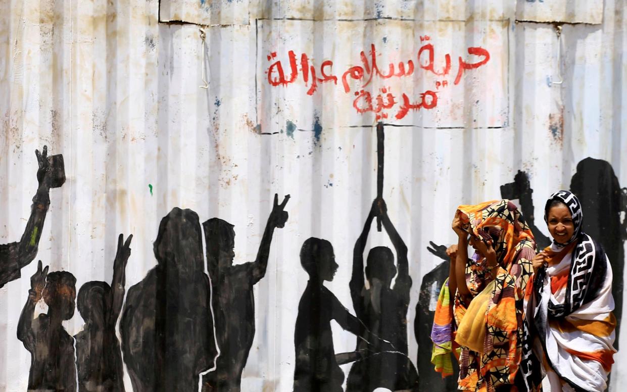 Civilians walk past graffiti reading in Arabic "Freedom, Peace, Justice and Civilian" in the Burri district of Khartoum - Reuters