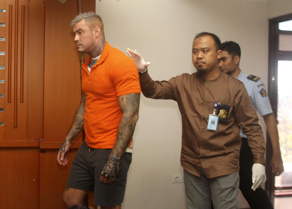 British national Terence Murrell, left, is escorted by immigration officers during a press conference in Bali, Indonesia, Tuesday, July 30, 2019. Indonesian authorities say they arrested the alleged British fugitive in Bali in possession of pornography and drugs. (AP Photo/Yoan Ari)