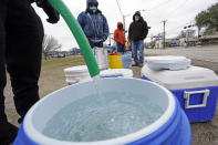 FILE - In this Feb. 18, 2021, file photo, a water bucket is filled as others wait in near freezing temperatures to use a hose from public park spigot in Houston. The snow and ice that crippled some states across the South has melted. But it has exposed the fragility of aging waterworks that experts have been warning about for years. Cities across Texas, Tennessee, Louisiana and Mississippi are still grappling with outages that crippled health care facilities and forced families to wait in line for potable water. (AP Photo/David J. Phillip, File)