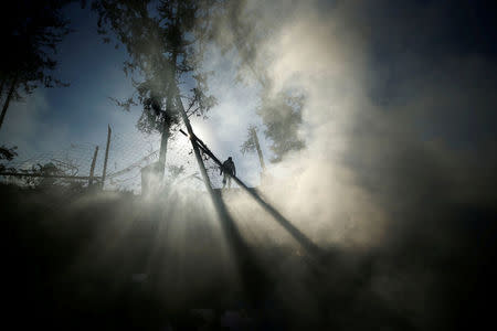 Smoke is seen as a Palestinian man inspects a militant target that was hit in an Israeli airstrike in the northern Gaza Strip December 9, 2017. REUTERS/Mohammed Salem TPX IMAGES OF THE DAY