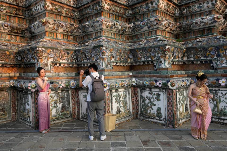 A Chinese tourist in traditional Thai dress poses for a photograph at Wat Arun or the "Temple of Dawn" in Bangkok, Thailand on Jan. 12, 2023. On Thursday, Aug. 10, 2023, China increased the number of countries that its big-spending tourists can visit by more than 70 following the lifting of its last COVID-19 travel restrictions.