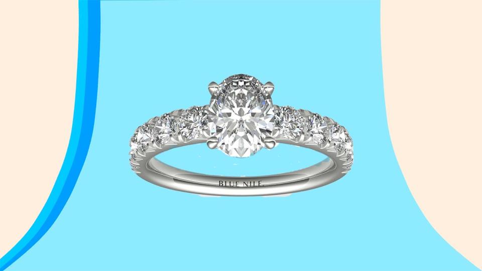 A French-pavé diamond hidden halo band is paired with an oval-shaped diamond center.