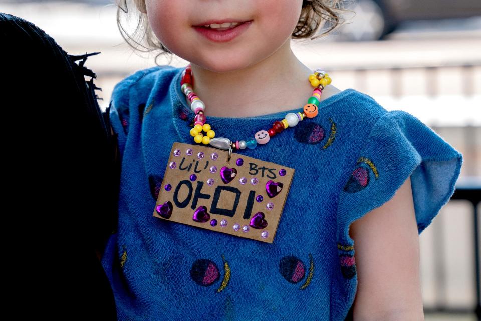 A child wears a homemade "Lil' BTS" necklace outside the White House.