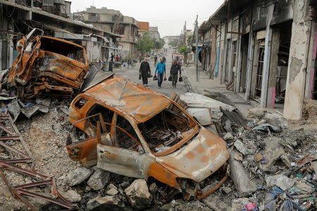 Displaced Iraqi men walks past destroyed vehicles as the battle between the Iraqi Counter Terrorism Service and Islamic State militants continues nearby, in western Mosul, Iraq, April 23, 2017. REUTERS/Marko Djurica