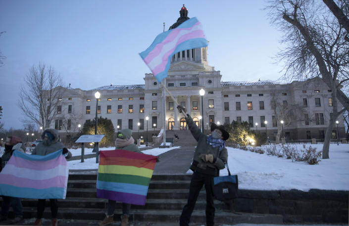 FILE - A group of LGBTQ advocates gathere outside the South Dakota Capitol in Pierre on Jan. 26, 2021, to protest a bill that would have banned people from updating the sex on their birth certificates. A Little Rock pharmacist's testimony before a legislative committee about gender affirming care for minors resulted in an Arkansas lawmaker asking about her genitalia. The exchange highlights the type of hostile rhetoric that transgender people say they’re facing at statehouses across the country. (AP Photo/Stephen Groves, File)