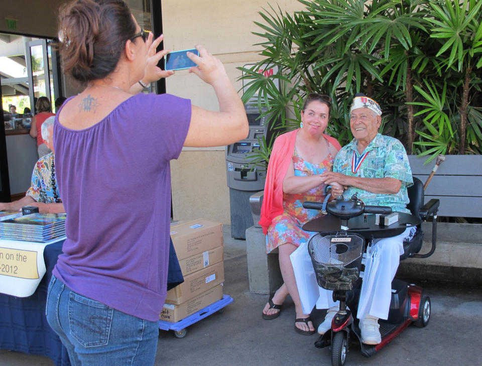 In this photo taken Nov. 22, 2013, Herb Weatherwax, right, poses for a photo with Raphaelle Yax of from Austin, Texas in Pearl Harbor, Hawaii. The 96-year-old retired electrician is one of four Pearl Harbor survivors who volunteers to greet visitors at the historic site. On Saturday is the 72nd anniversary of the 1941 attack by Japan on Pearl Harbor. (AP Photo/Audrey McAvoy)