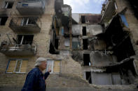 A woman walks in front of a building damaged by shelling in Horenka, on the outskirts of Kyiv, Ukraine, Wednesday, May 25, 2022. (AP Photo/Natacha Pisarenko)
