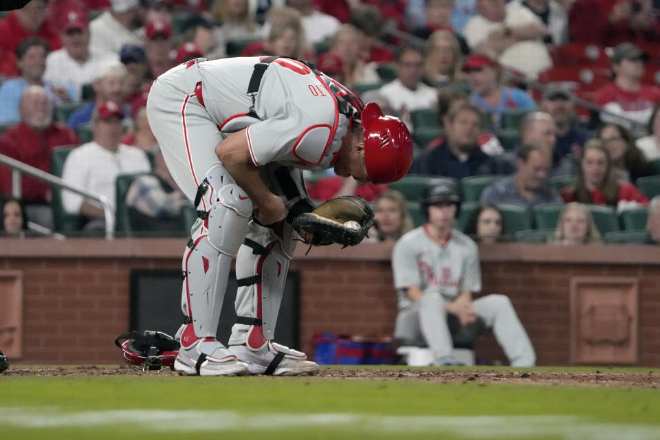 Philadelphia Phillies catcher J.T. Realmuto doubles over after being injured during the seventh inning of a baseball game against the St. Louis Cardinals Tuesday, April 9, 2024, in St. Louis. Realmuto left the game. (AP Photo/Jeff Roberson)