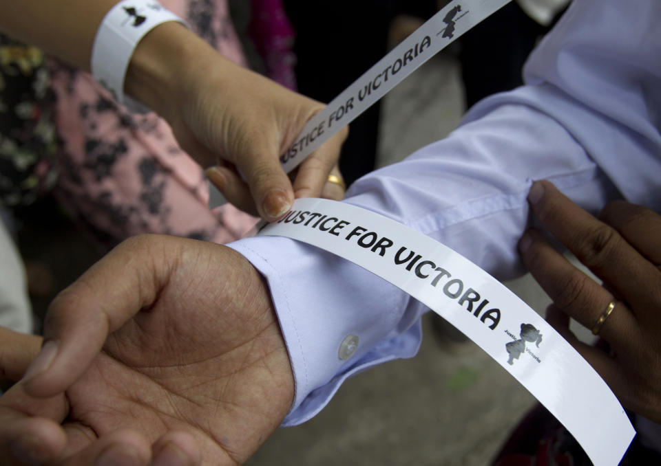 A volunteer helps to wear a wrist band as they gather for a protest in Yangon, Myanmar Saturday, July 6, 2019. Hundreds of people marched to Myanmar’s Central Investigation Department on Saturday in Yangon to demand justice for a 2-year-old girl who was allegedly raped in the country’s capital in May. (AP Photo/Thein Zaw)