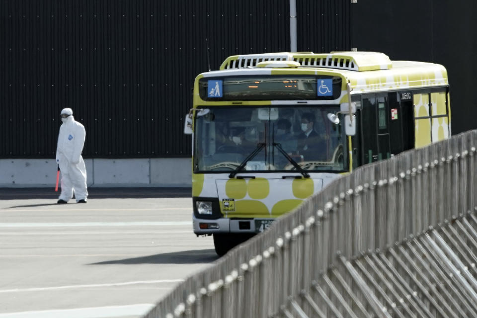 A bus drives near the quarantined Diamond Princess cruise ship anchored at a port in Yokohama, near Tokyo, Wednesday, Feb. 19, 2020. The cruise ship begins letting passengers off the boat on Wednesday after it's been in quarantined for 14 days. (AP Photo/Eugene Hoshiko)