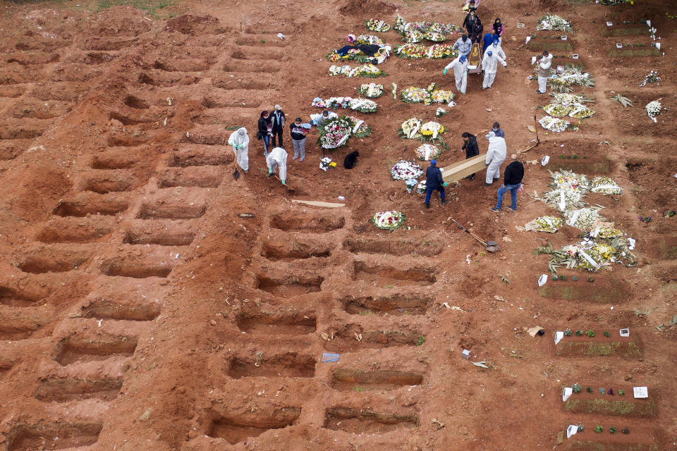 FILE - In this July 15, 2020, file photo, cemetery workers in protective clothing bury three victims of COVID-19 at the Vila Formosa cemetery in Sao Paulo, Brazil. Not just President Donald Trump, who has lambasted the World Health Organization, but the likes of his political bedfellows who have also underplayed the coronavirus and themselves also been infected by it: Brazil's Jair Bolsonaro and Britain's Boris Johnson. (AP Photo/Andre Penner, File)