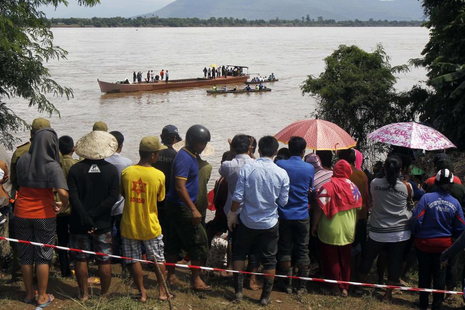 Villagers gather on banks of Mekong river as rescue personnel on boats search the crash site of an ATR-72 turboprop plane, in Laos, near Pakse