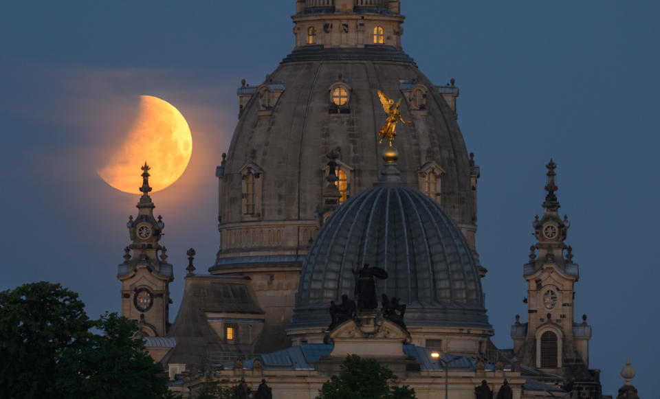 The moon sets in the morning during a partial lunar eclipse behind the Frauenkirche and the dome of the Kunstakedmie with the angel 