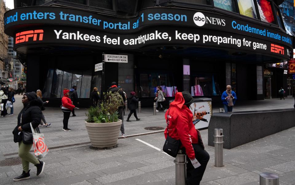 A digital ticker-tape board on Times Square displays news of the earthquake