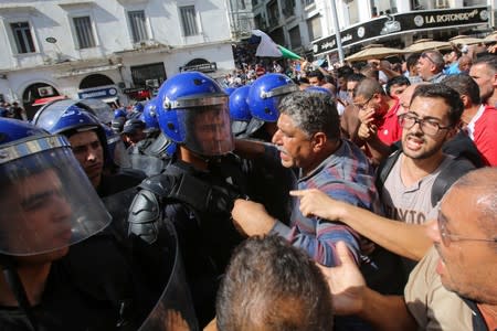 Demonstrators confront police officers during a protest against a proposed new hydrocarbons law in Algiers