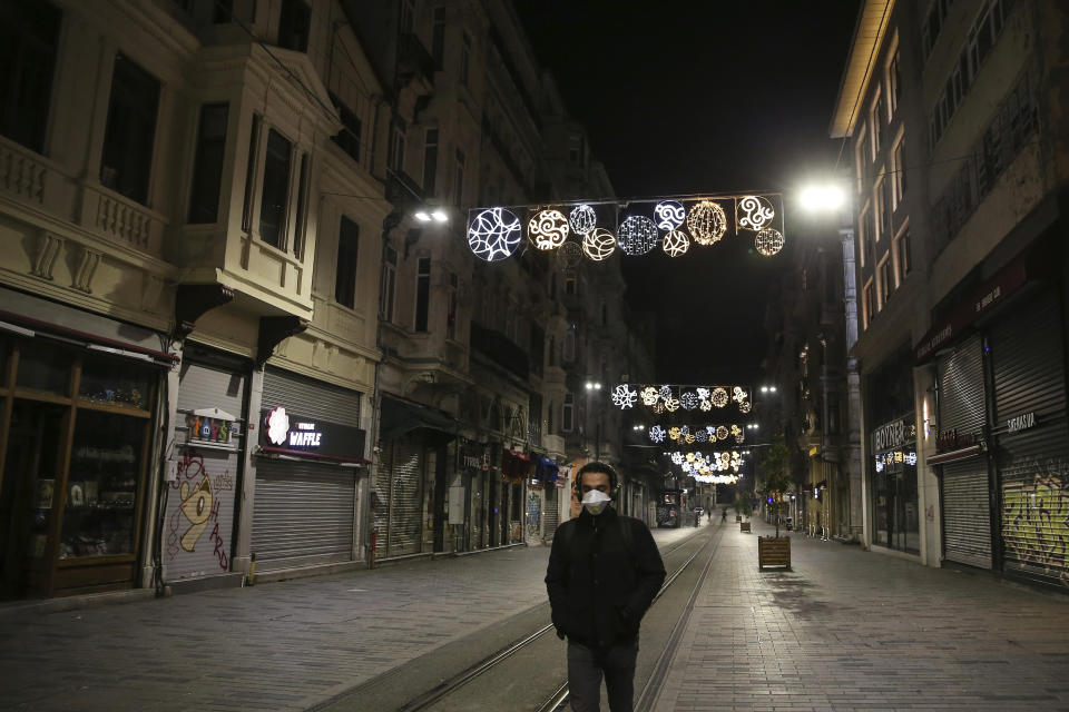 A man wearing a mask to protect against the spread of the coronavirus, walks on the deserted Istiklal Street, the main shopping street in Istanbul, in Istanbul, late Friday, April 3, 2020. The new coronavirus causes mild or moderate symptoms for most people, but for some, especially older adults and people with existing health problems, it can cause more severe illness or death. (AP Photo/Emrah Gurel)