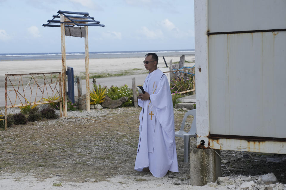 A priest listens to ceremonies at the Philippine-occupied Thitu island, locally called Pag-asa island, on Friday, Dec. 1, 2023 at the disputed South China Sea. The Philippine coast guard inaugurated a new monitoring base Friday on a remote island occupied by Filipino forces in the disputed South China Sea as Manila ramps up efforts to counter China's increasingly aggressive actions in the strategic waterway. (AP Photo/Aaron Favila)