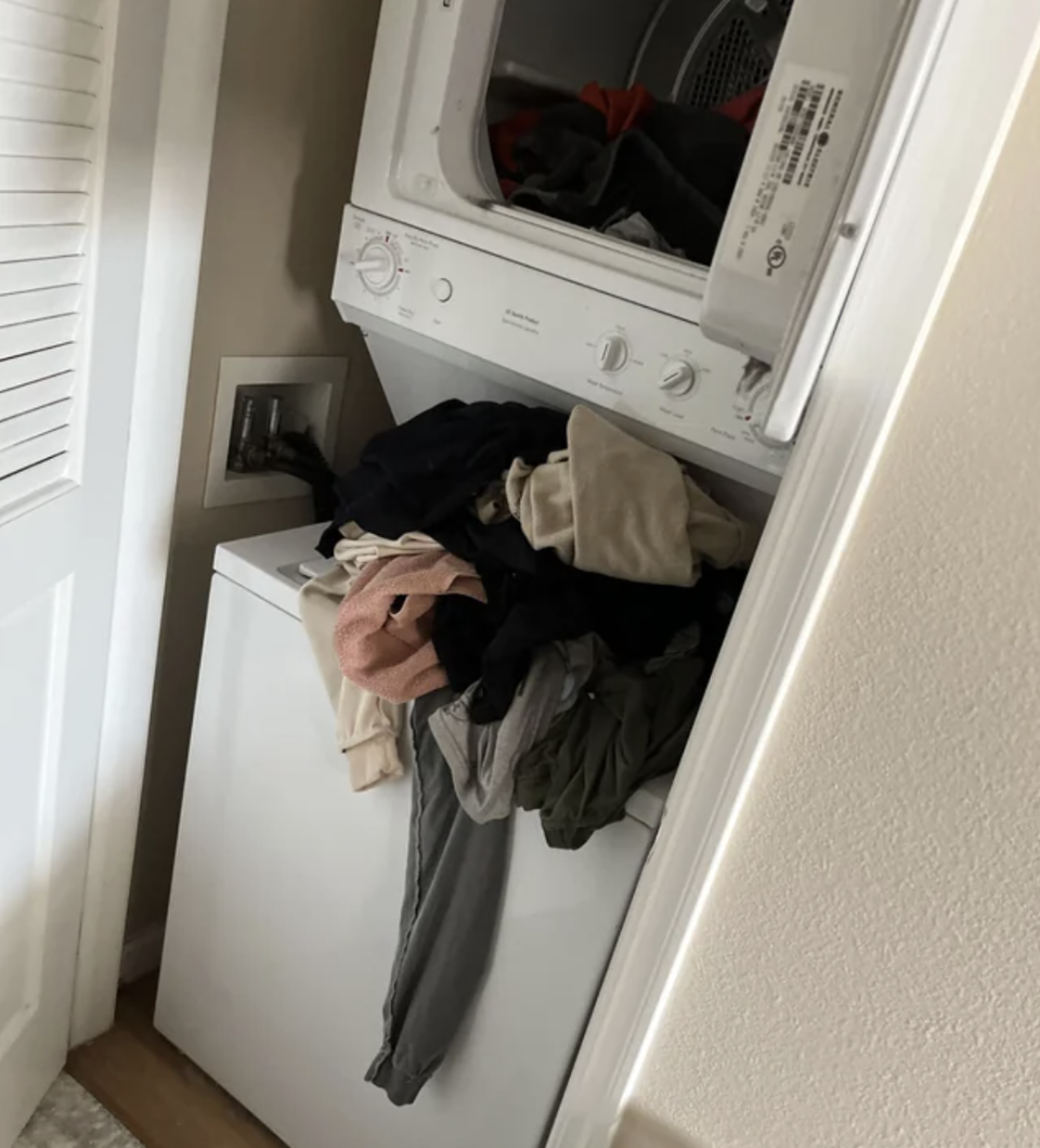 Pile of clothes sitting on top of a laundry machine