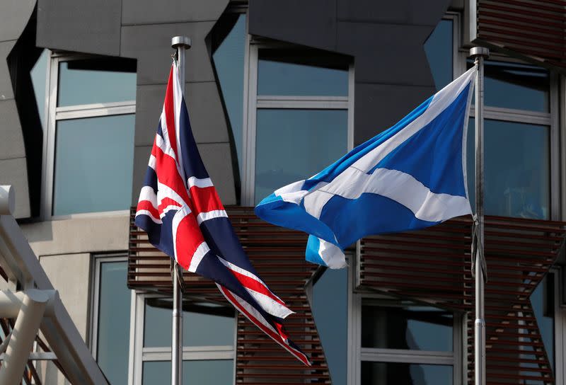 A Scottish flag flies next to British Union Jack flag outside the Scottish Parliament in Edinburgh