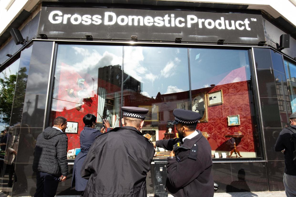 Police officers and members of the public gather outside Gross Domestic Product, a homeware store that is being launched in South London by Banksy: PA Wire/PA Images