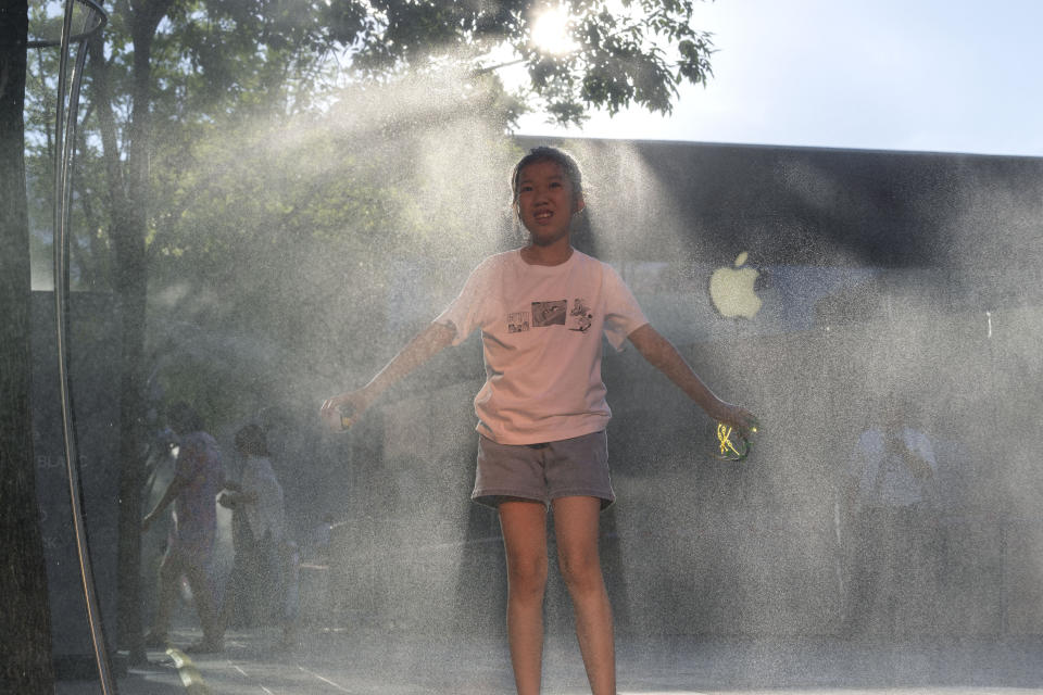 A girl plays near a mist machine to cool off from the summer heat in Beijing, Saturday, June 15, 2024. (AP Photo/Ng Han Guan)