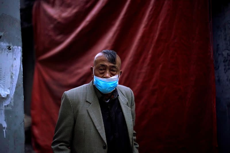 A resident wearing a face mask is seen at a blocked residential area after the lockdown was lifted in Wuhan