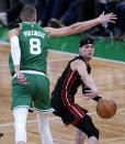 Miami Heat guard Tyler Herro, right, passes the ball while covered by Boston Celtics center Kristaps Porzingis (8) during the second half Game 2 of an NBA basketball first-round playoff series Wednesday, April 24, 2024, in Boston. (AP Photo/Charles Krupa)