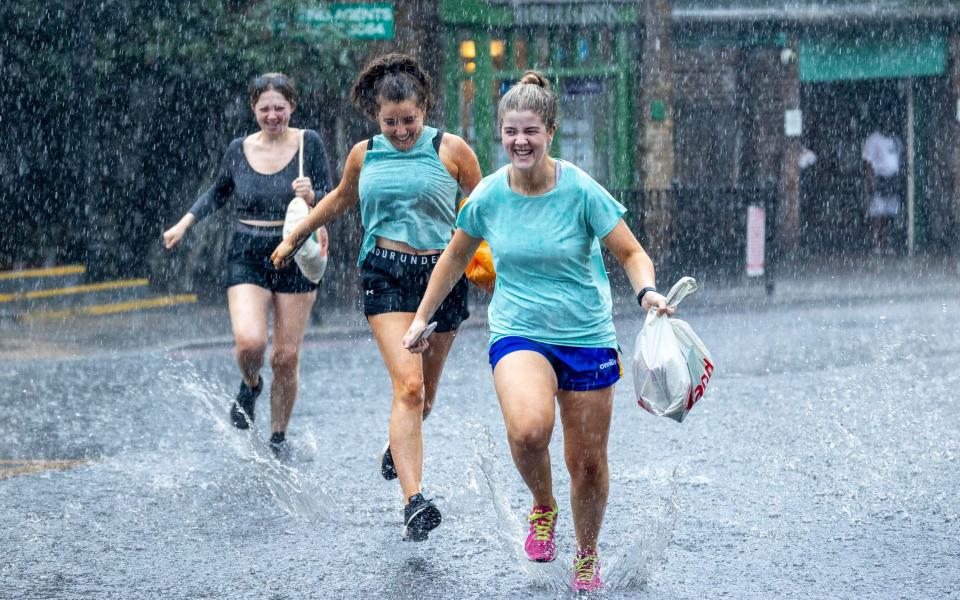 Three young women sprint for cover in Highgate, North London - Gavin Rodgers/ Pixel8000