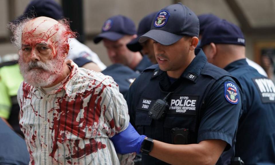 A climate crisis activist covered in fake blood is arrested in New York City during the Extinction Rebellion demonstration.